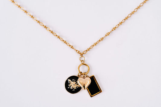Fine detailed chain with hanging gold disc and 3 charms; round black enamel bee, square black charm and delicate 3D heart